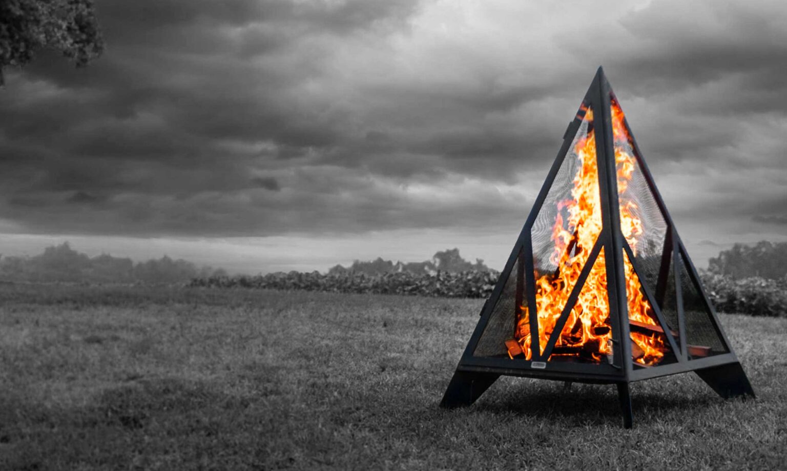 Pyramid fireplace in field. Background in black and white