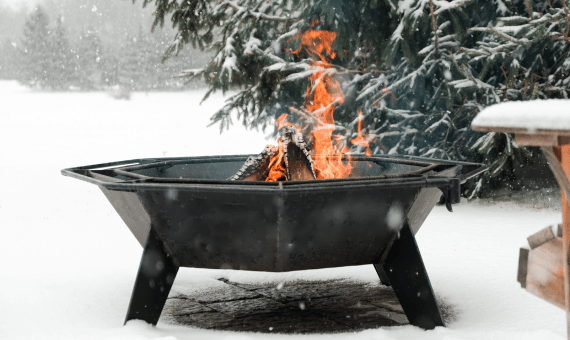 Iron Embers octagonal cottager fire pit burning in the snow.