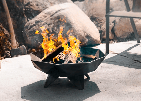 Blazing fire in a small steel fire pit on a stone patio