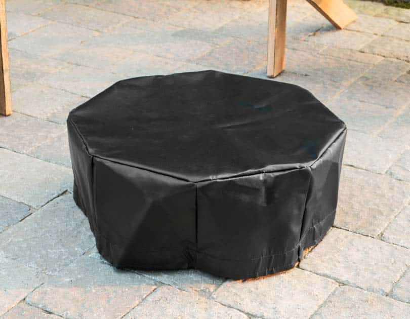 Form fitting vinyl tarp cover for a small steel fire pit on a patio