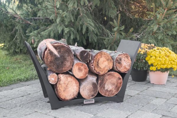 Fire wood in a tamarack log holder on a stone patio