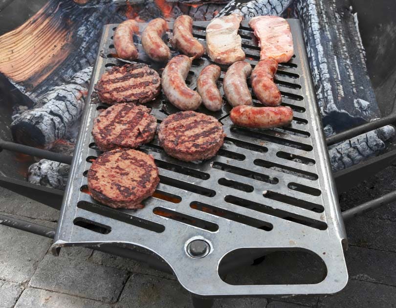 Plate BBQ grill with burgers and sausages over the fire