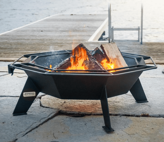 Burning Cottager fire pit on a large patio next to a lake and dock