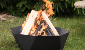 Small fire ring on the grass with a large fire burning